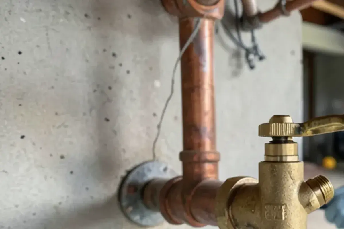 Interior shutoff valve for an outdoor spigot with its small drain cap open over a cup